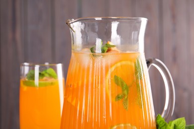 Photo of Freshly made lemonade in jug, glass and mint against blurred background