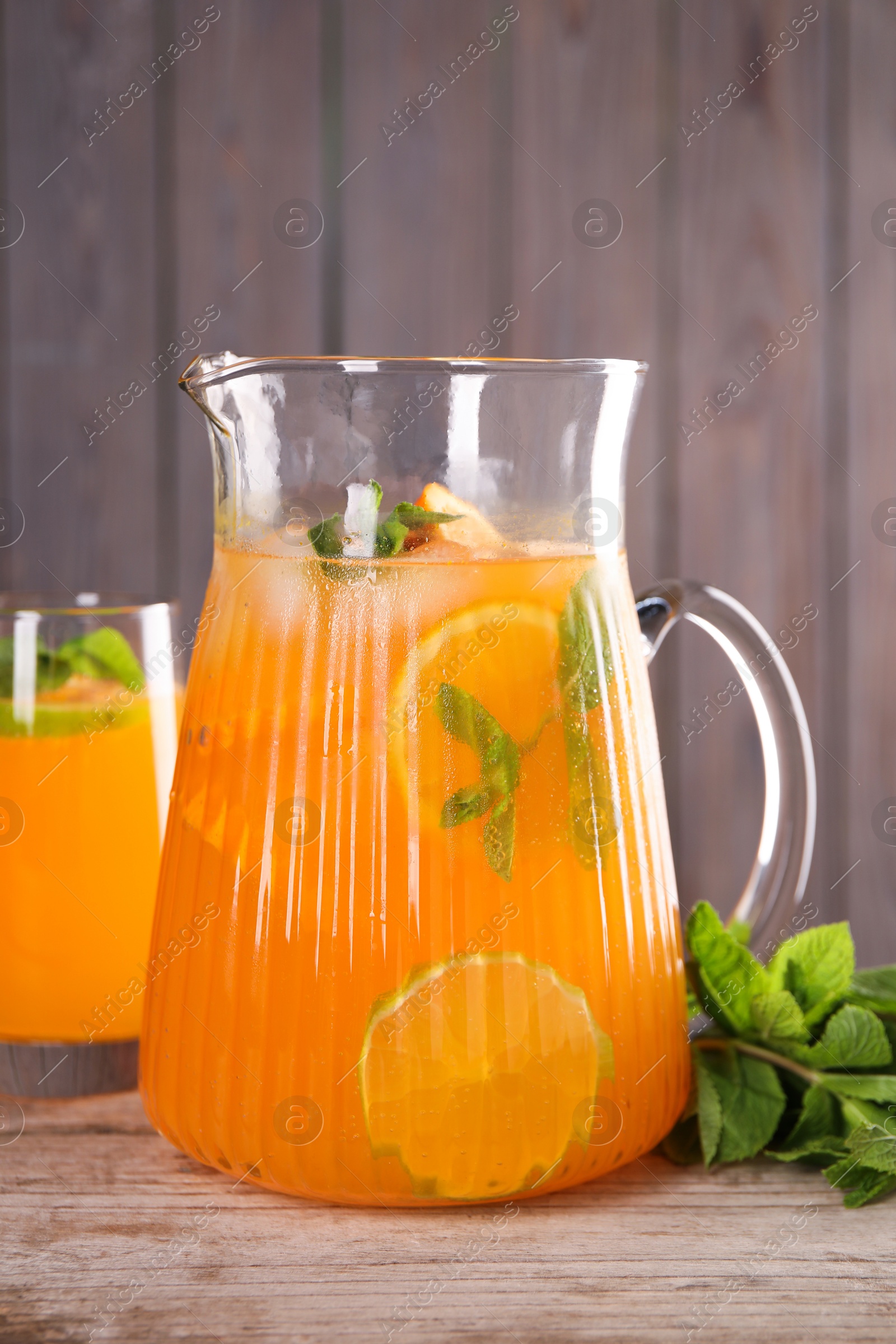 Photo of Freshly made lemonade in jug, glass and mint on wooden table