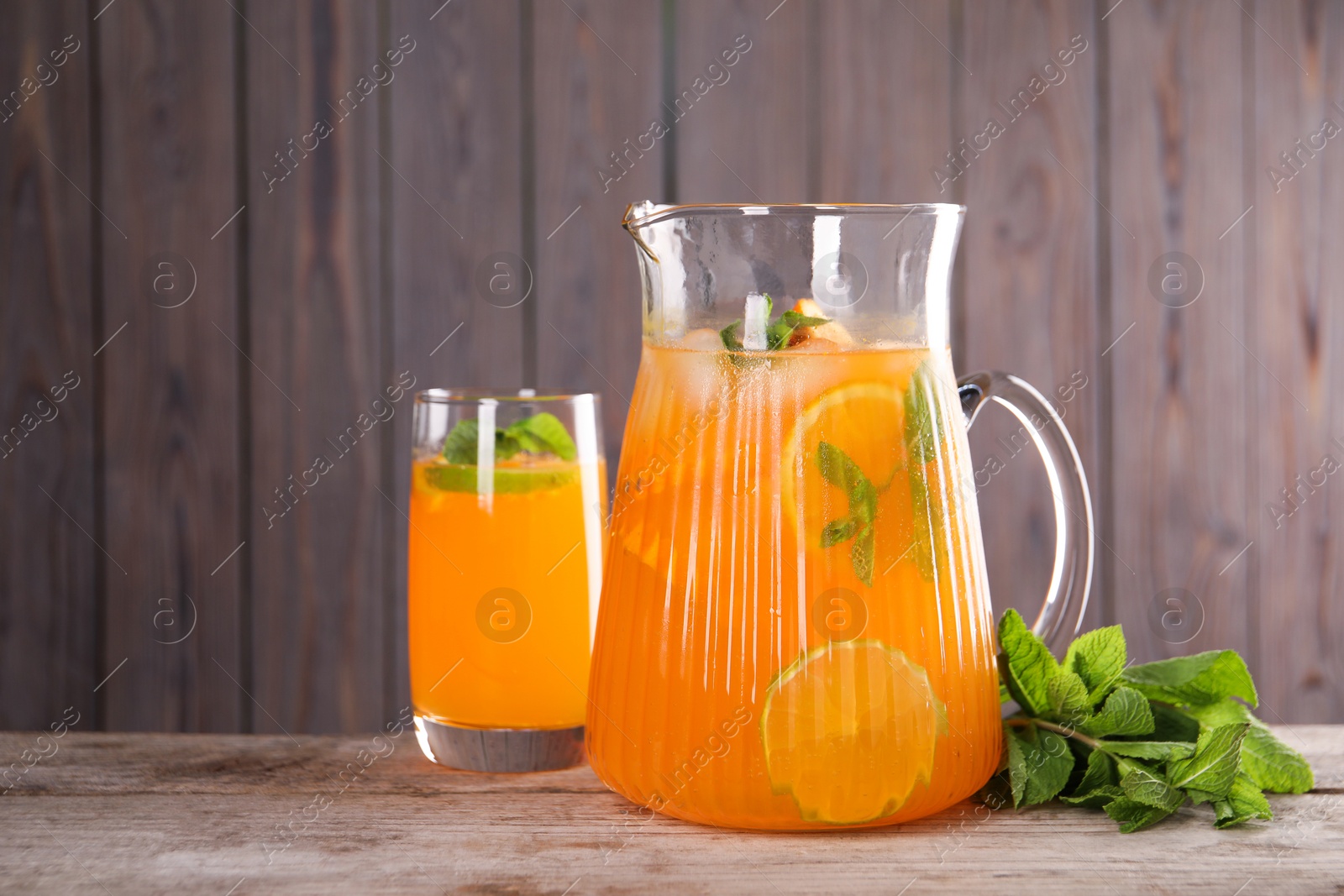 Photo of Freshly made lemonade in jug, glass and mint on wooden table, space for text