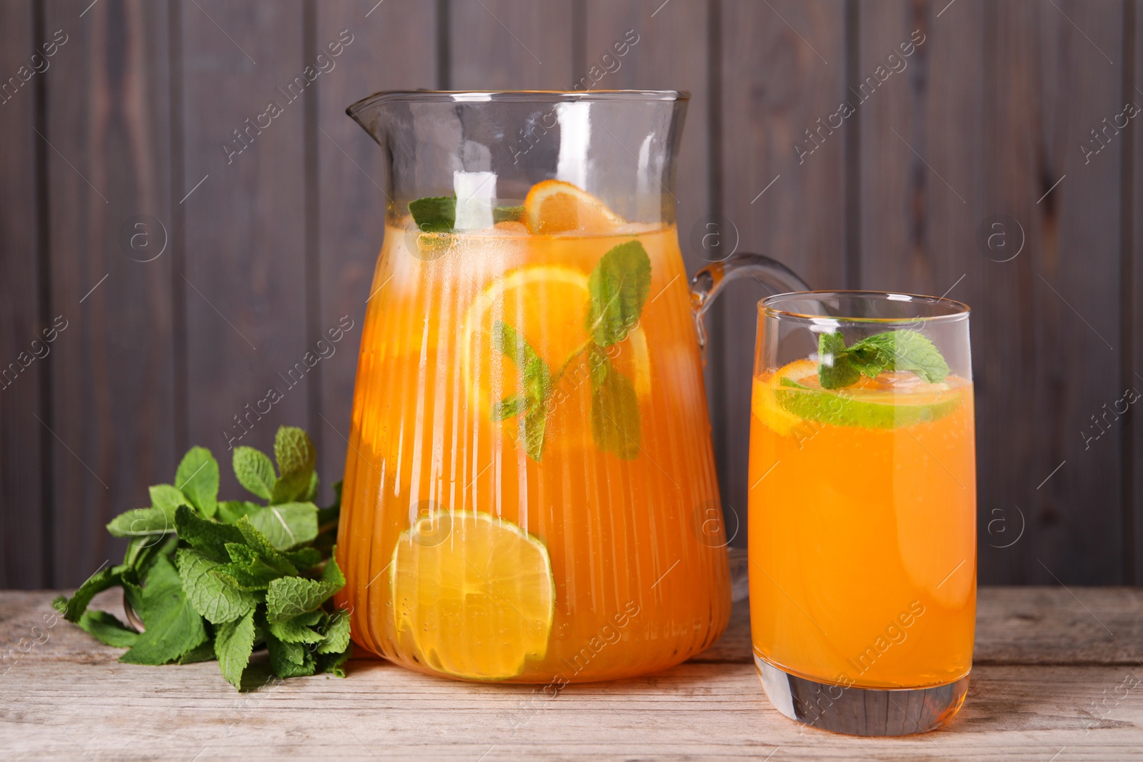 Photo of Freshly made lemonade in jug, glass and mint on wooden table