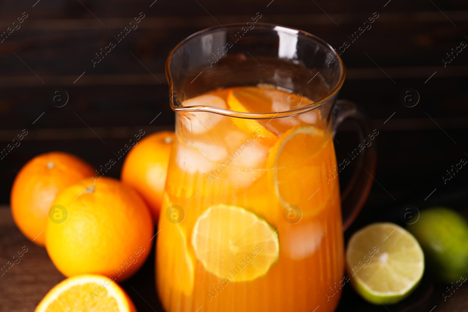 Photo of Freshly made lemonade in jug and citrus fruits on table