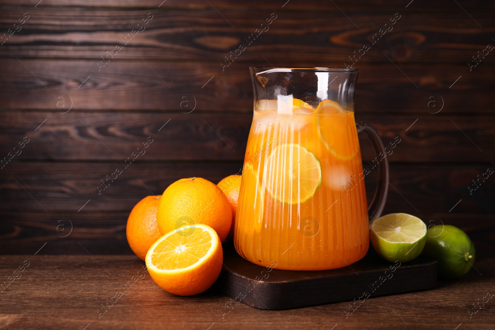 Photo of Freshly made lemonade in jug and citrus fruits on wooden table