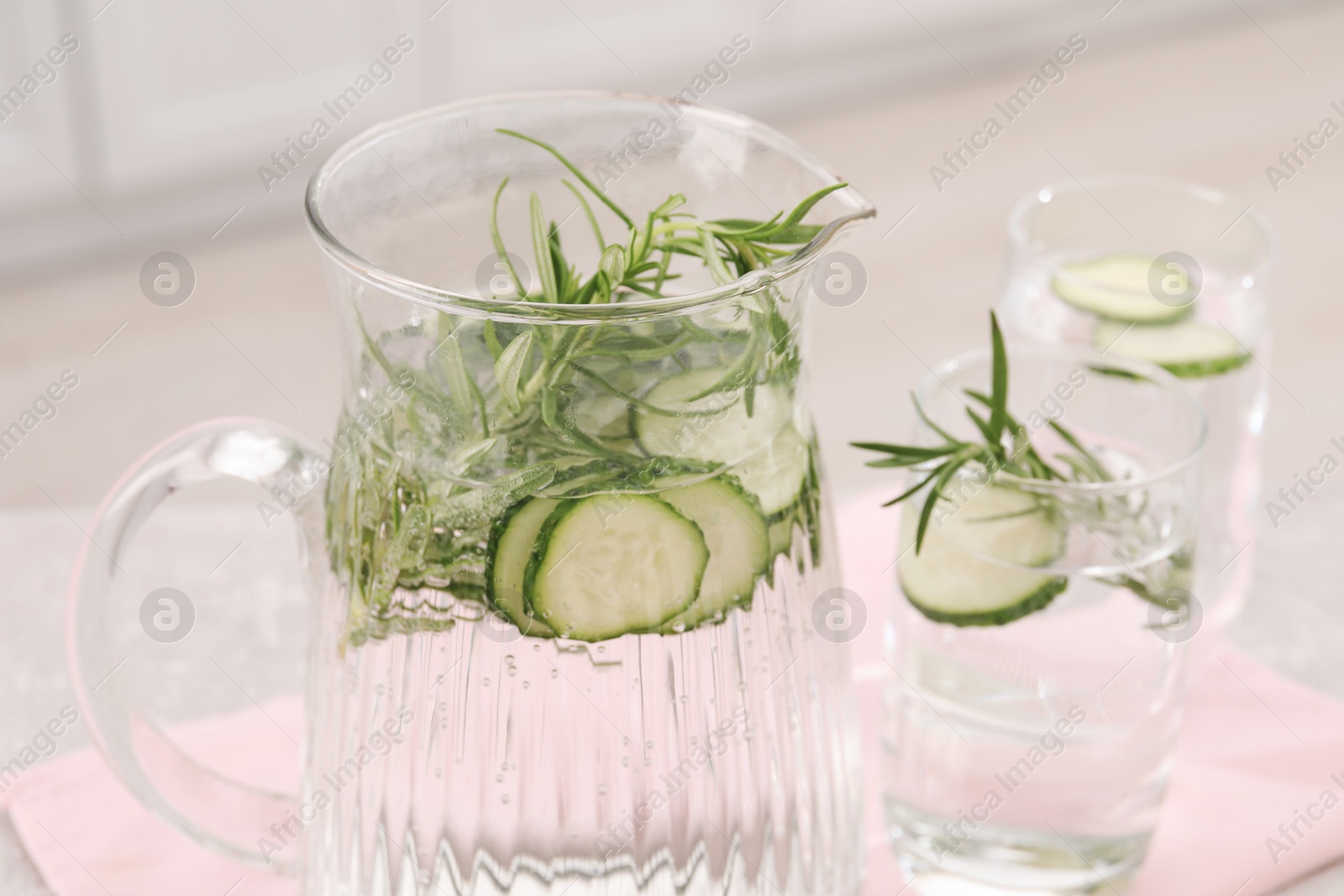 Photo of Refreshing cucumber water with rosemary on table in kitchen, closeup