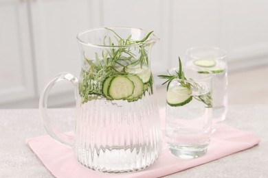 Photo of Refreshing cucumber water with rosemary on table in kitchen, closeup