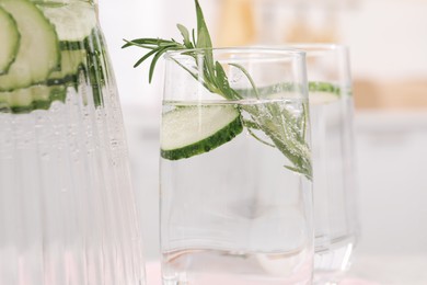 Refreshing cucumber water with rosemary on blurred background, closeup