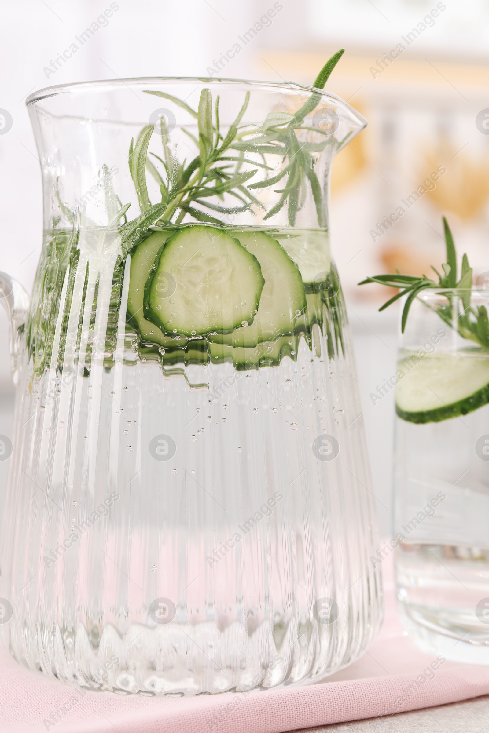 Photo of Refreshing cucumber water with rosemary on table, closeup