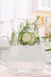 Refreshing cucumber water with rosemary on table, closeup