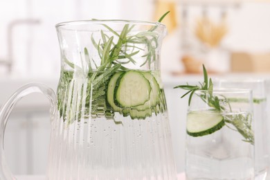 Refreshing cucumber water with rosemary on blurred background, closeup