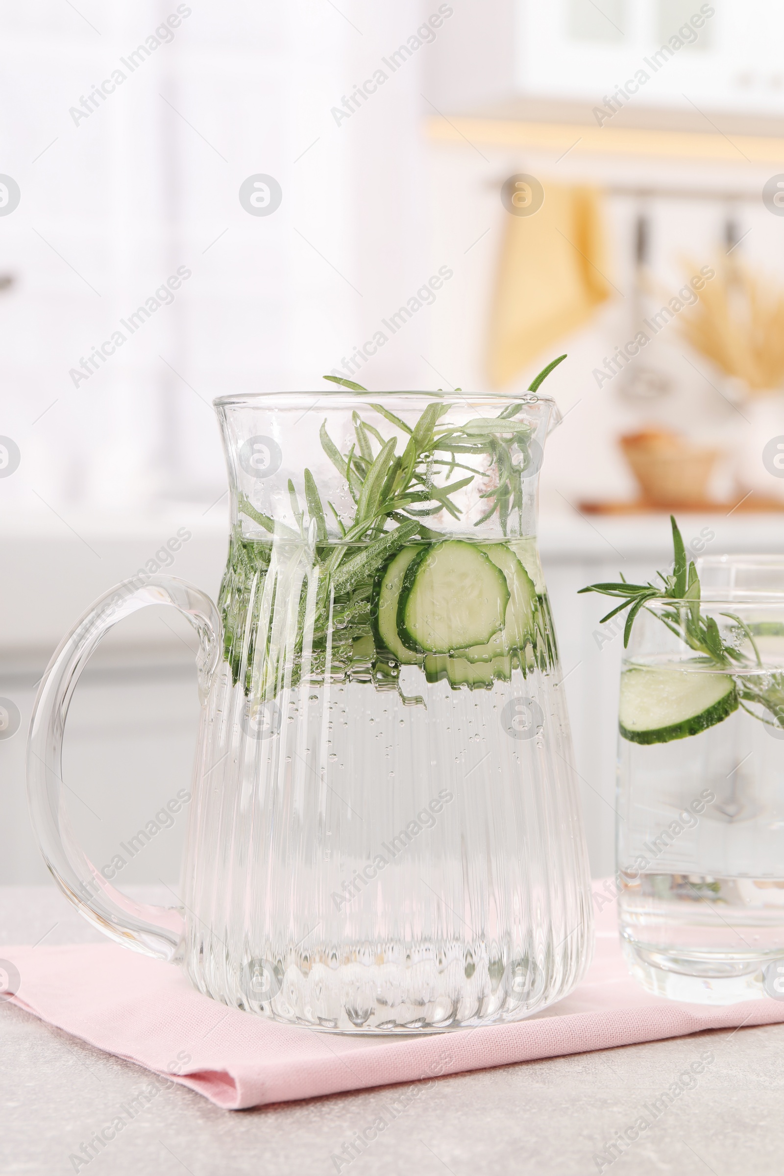 Photo of Refreshing cucumber water with rosemary on table in kitchen