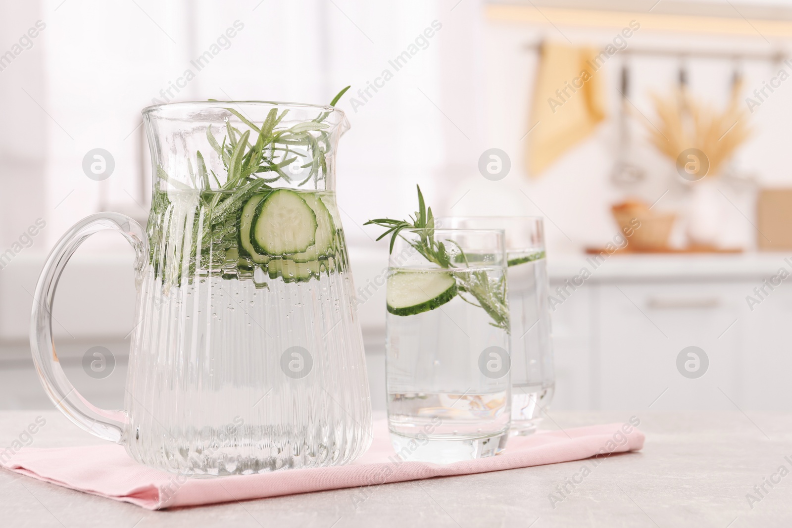 Photo of Refreshing cucumber water with rosemary on table in kitchen. Space for text