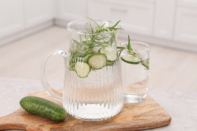 Photo of Refreshing cucumber water with rosemary and vegetable on table