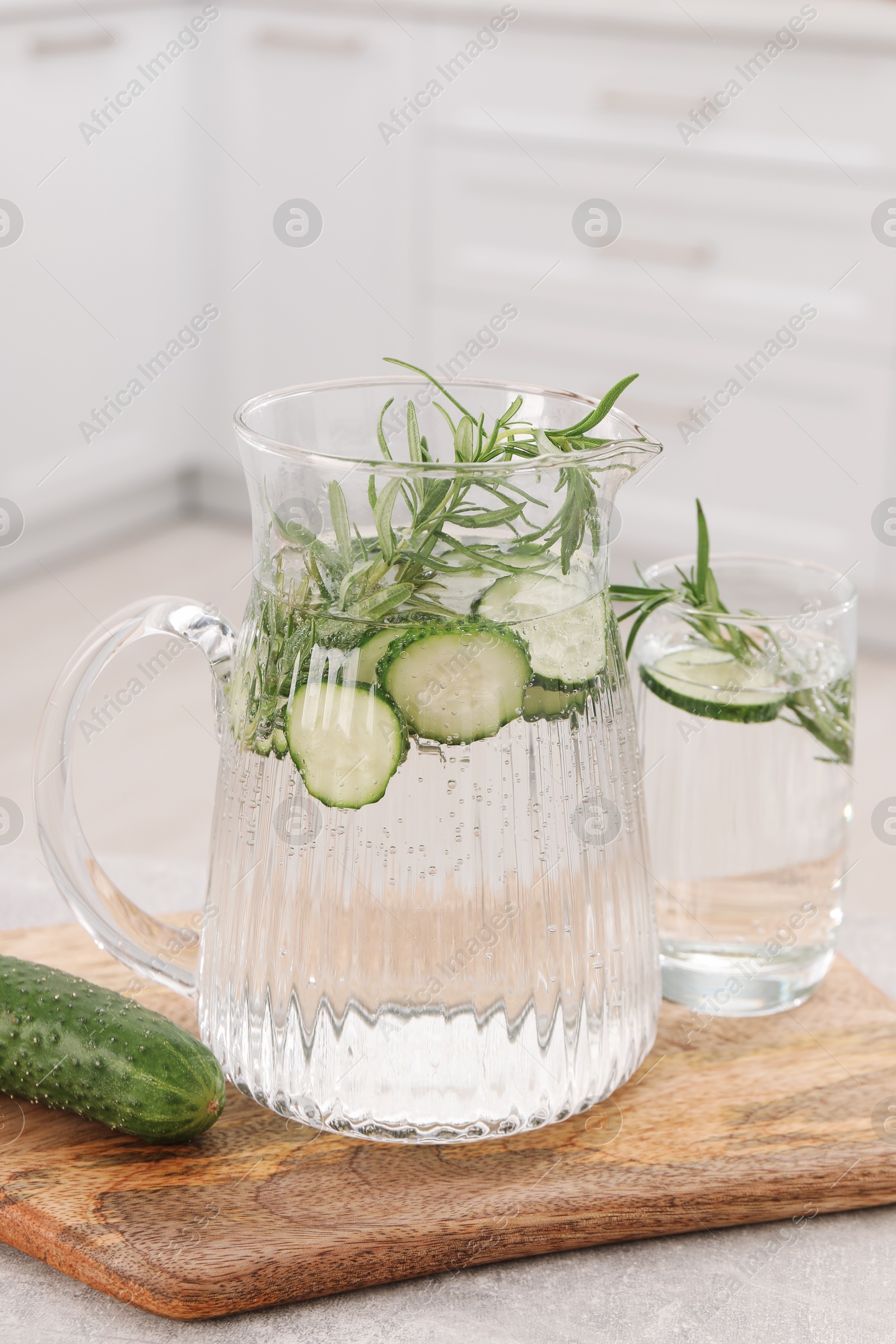 Photo of Refreshing cucumber water with rosemary and vegetable on table