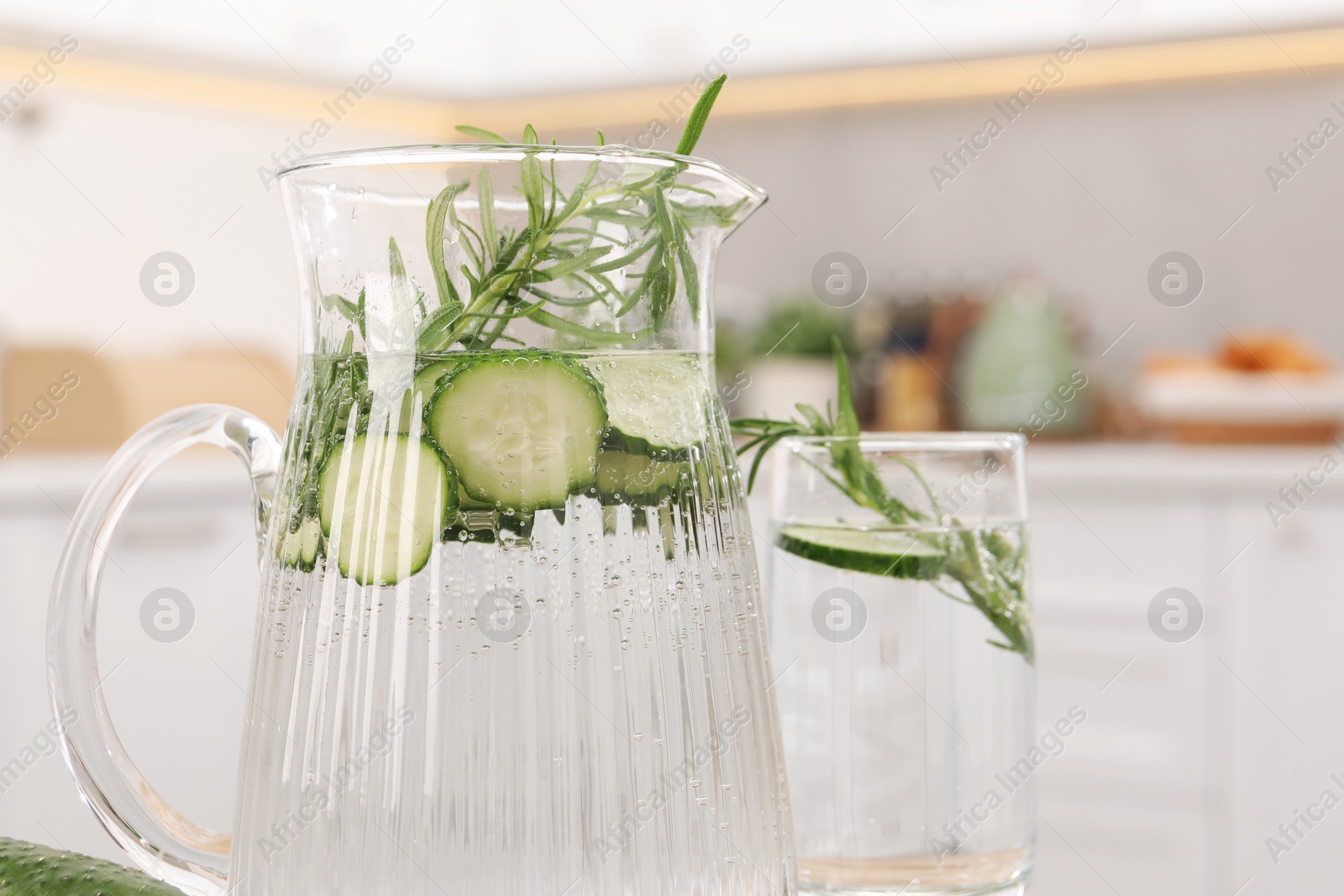 Photo of Refreshing cucumber water with rosemary in kitchen, closeup