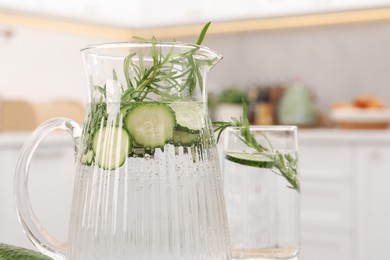 Refreshing cucumber water with rosemary in kitchen, closeup