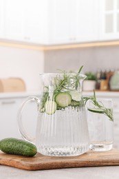 Refreshing cucumber water with rosemary and vegetable on table in kitchen