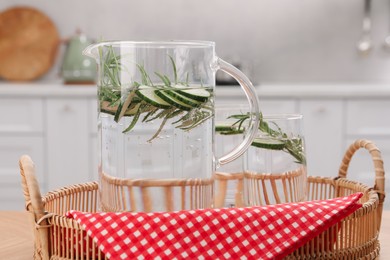 Refreshing cucumber water with rosemary on table, closeup