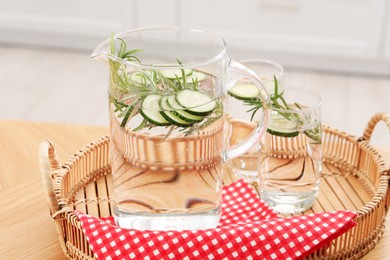 Photo of Refreshing cucumber water with rosemary in jug and glasses on wooden table, closeup