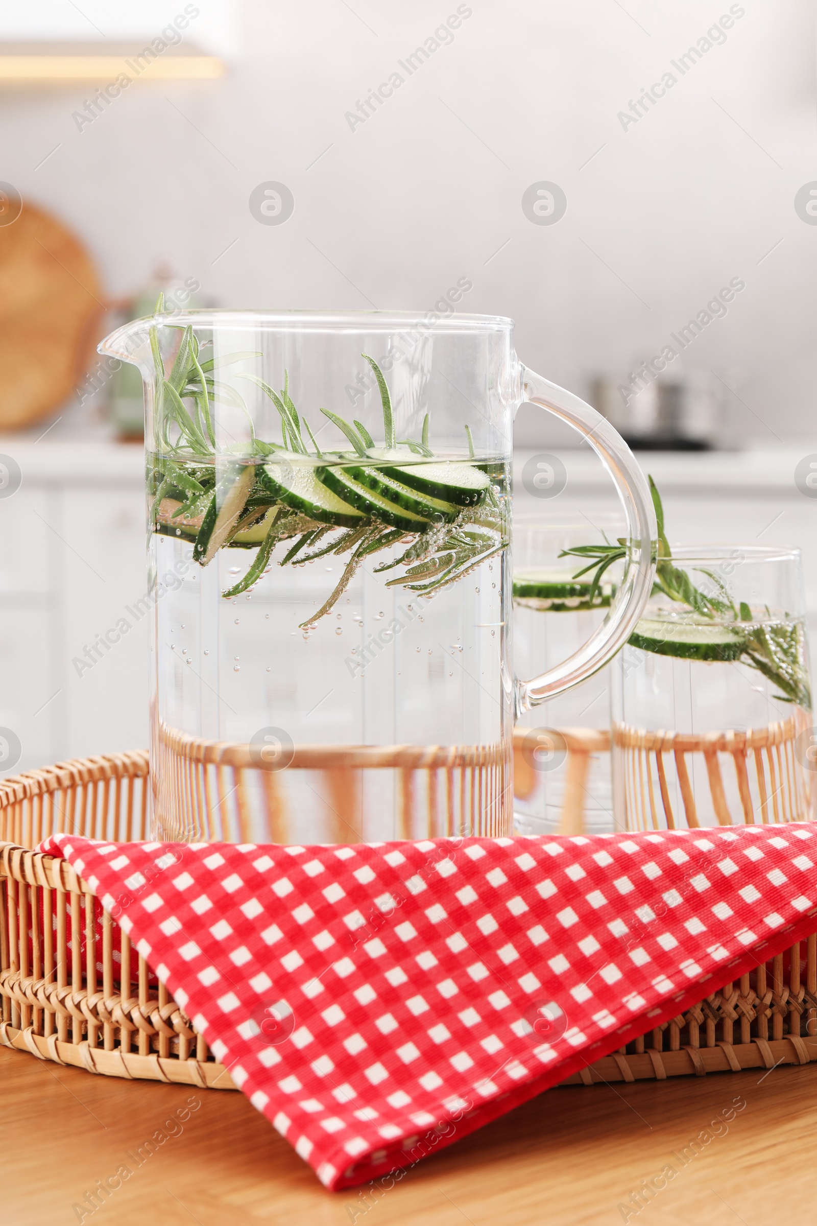 Photo of Refreshing cucumber water with rosemary in jug and glass on wooden table