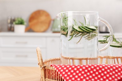 Photo of Refreshing cucumber water with rosemary in jug and glasses on wooden table. Space for text