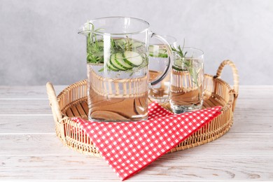 Photo of Refreshing cucumber water with rosemary in jug and glass on light wooden table