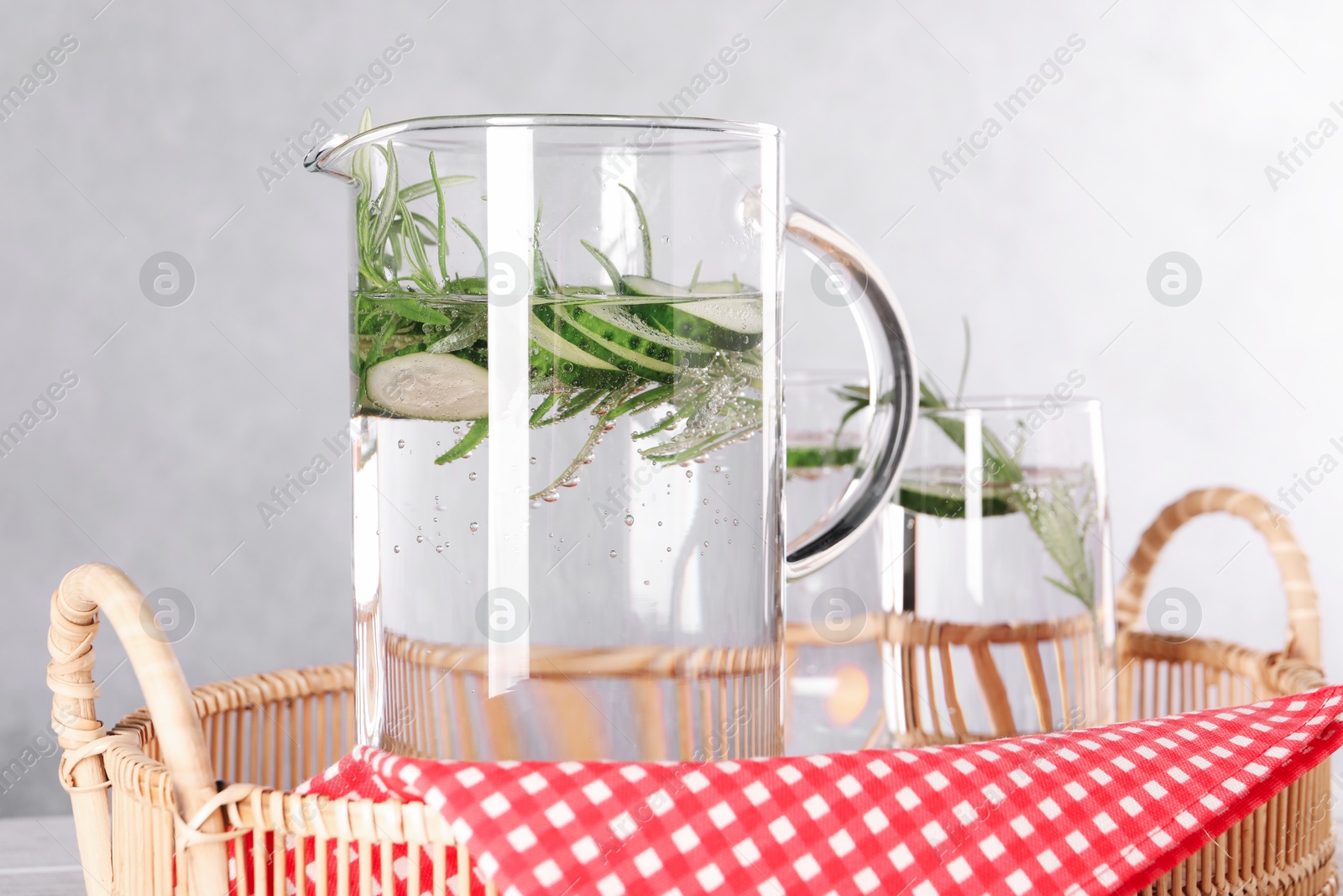 Photo of Refreshing cucumber water with rosemary in jug and glass on table, closeup