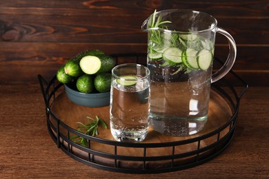 Tray with refreshing cucumber water with rosemary and vegetable on wooden table