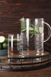 Photo of Tray with refreshing cucumber water with rosemary and vegetable on wooden table