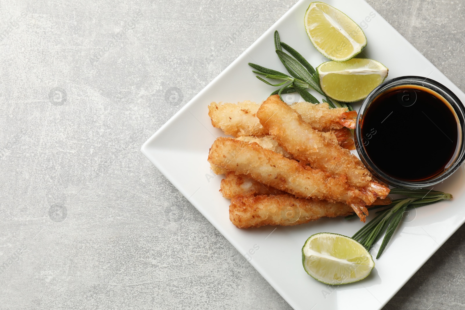 Photo of Delicious breaded fried shrimps served on grey table, top view. Space for text