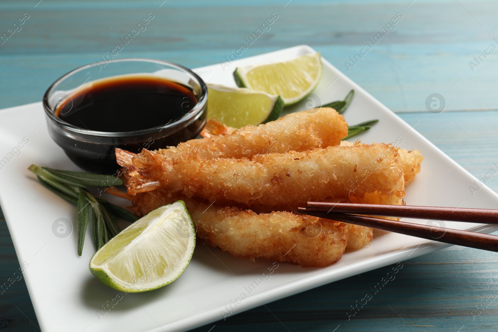 Photo of Delicious breaded fried shrimps served on light blue wooden table, closeup