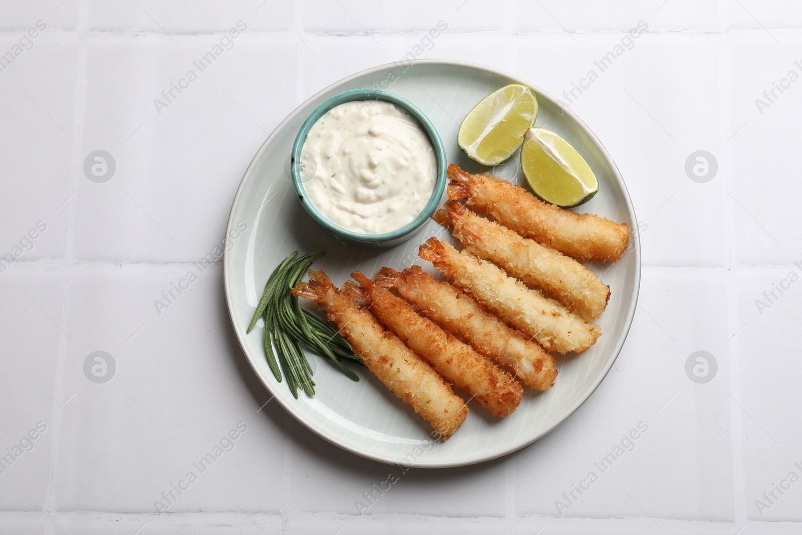 Photo of Delicious breaded fried shrimps served on white tiled table, top view