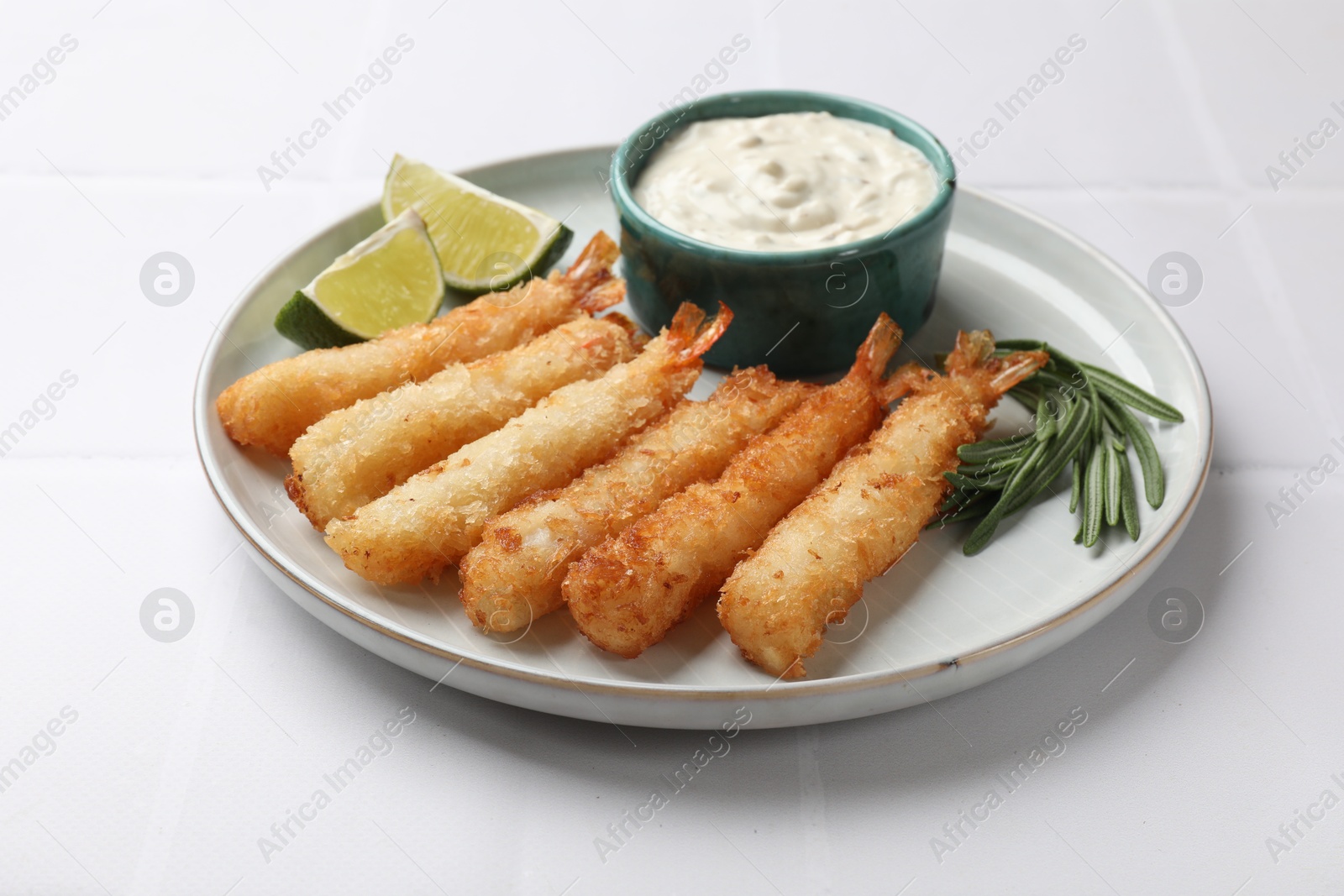 Photo of Delicious breaded fried shrimps served on white tiled table