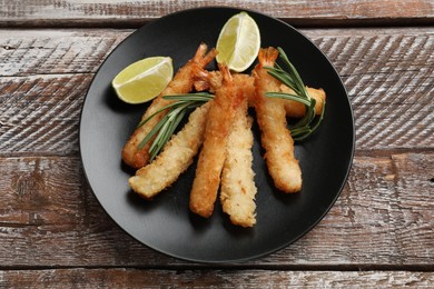 Delicious breaded fried shrimps served on wooden table, top view