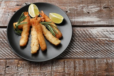 Photo of Delicious breaded fried shrimps served on wooden table, top view. Space for text