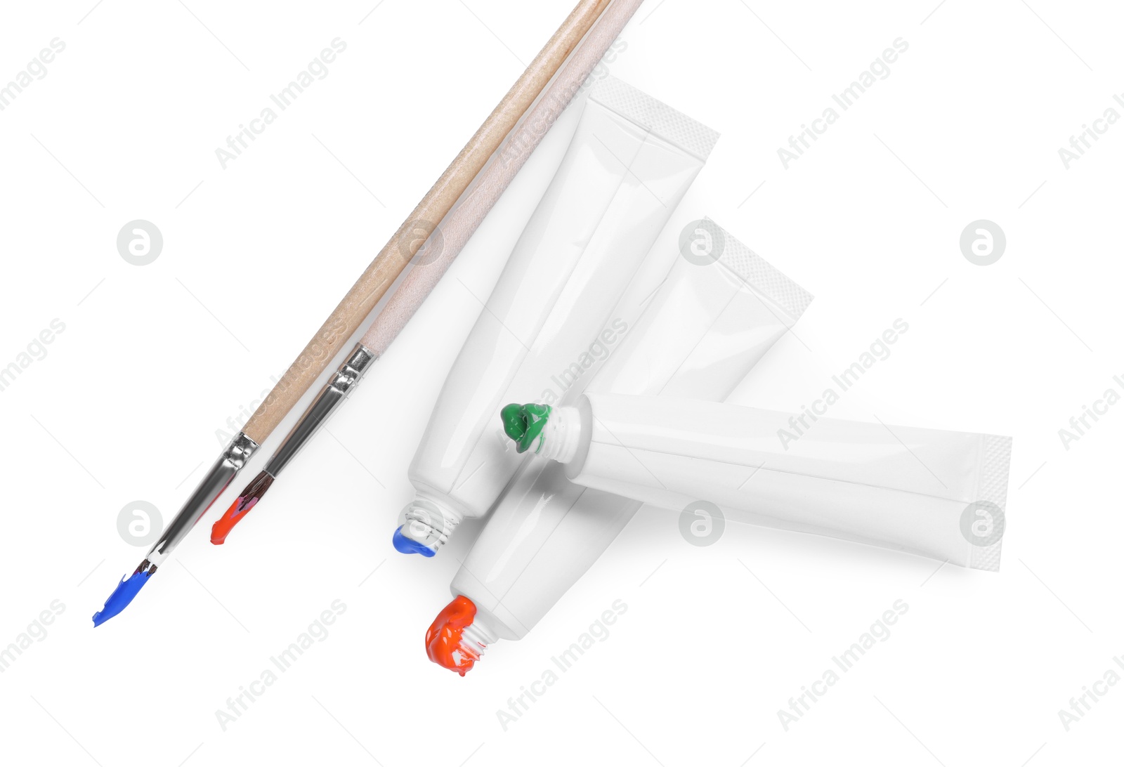 Photo of Tubes with colorful paints and brushes isolated on white, top view