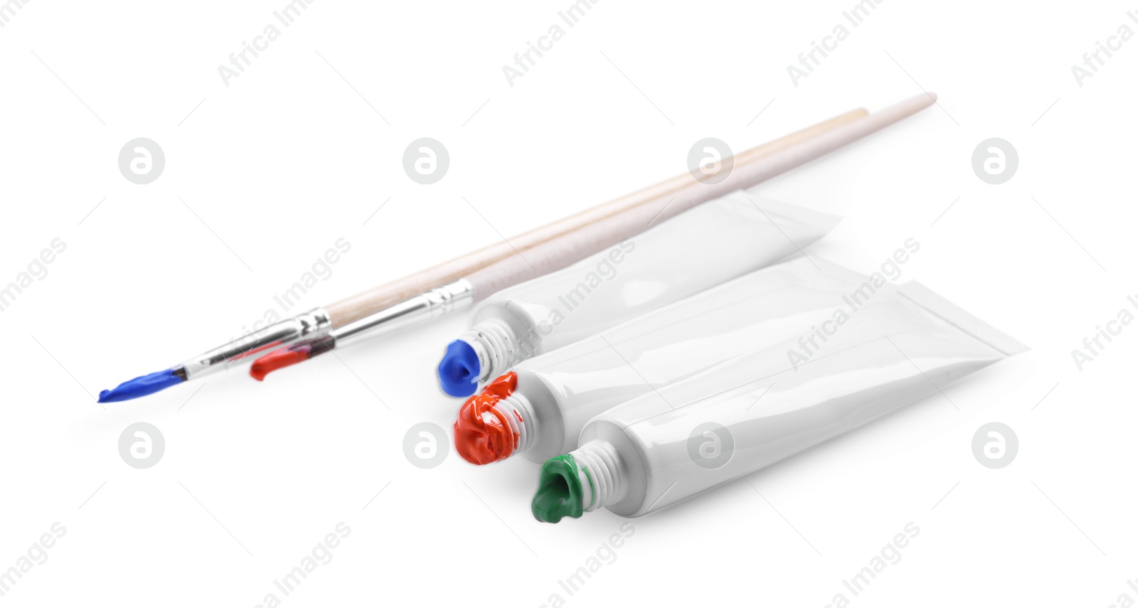 Photo of Tubes with colorful paints and brushes isolated on white