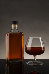 Bottle and glass with whiskey on table against gray background