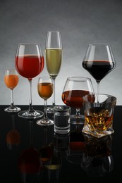 Photo of Glasses with different alcoholic drinks on table against gray background