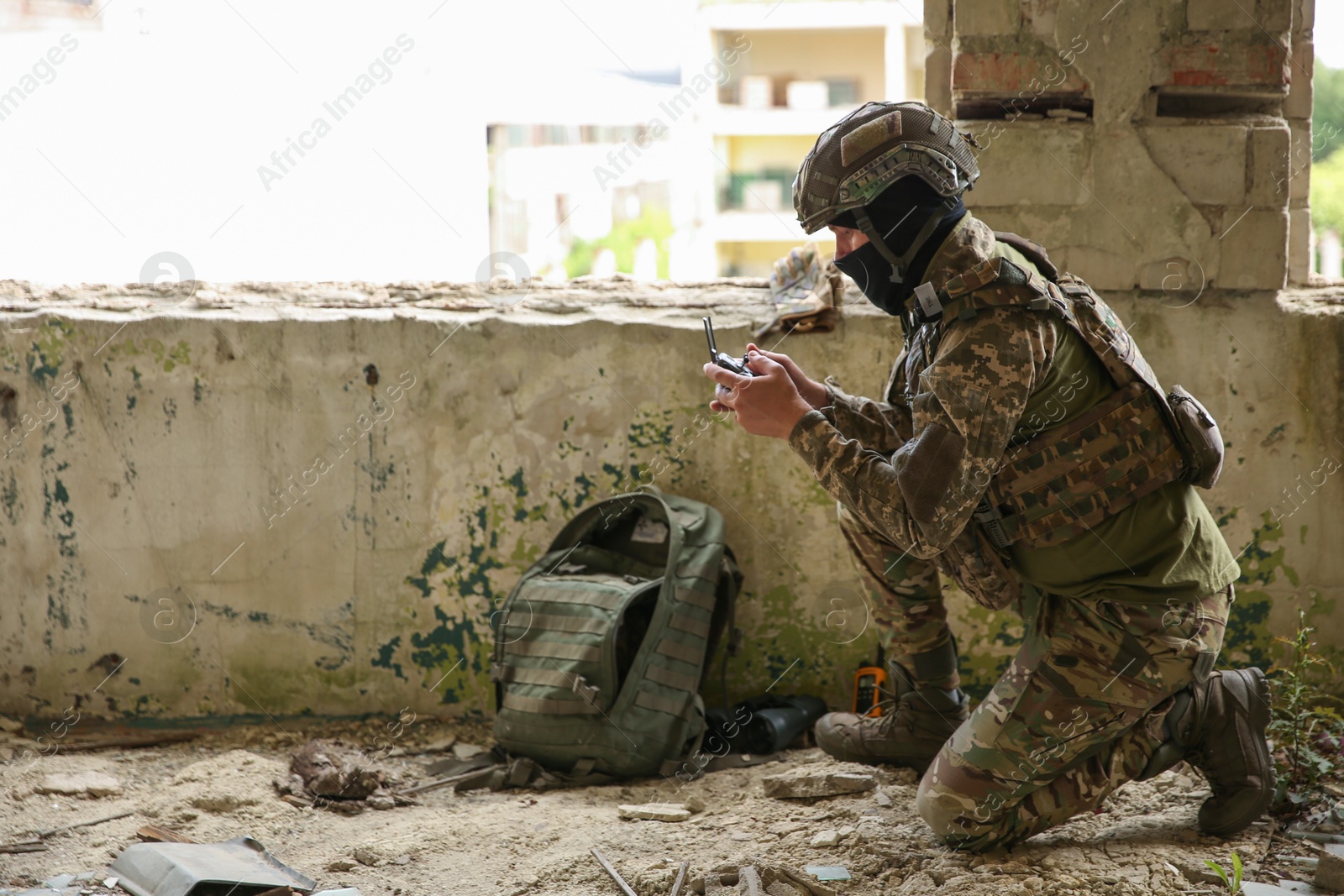 Photo of Military mission. Soldier in uniform with drone controller inside abandoned building, space for text