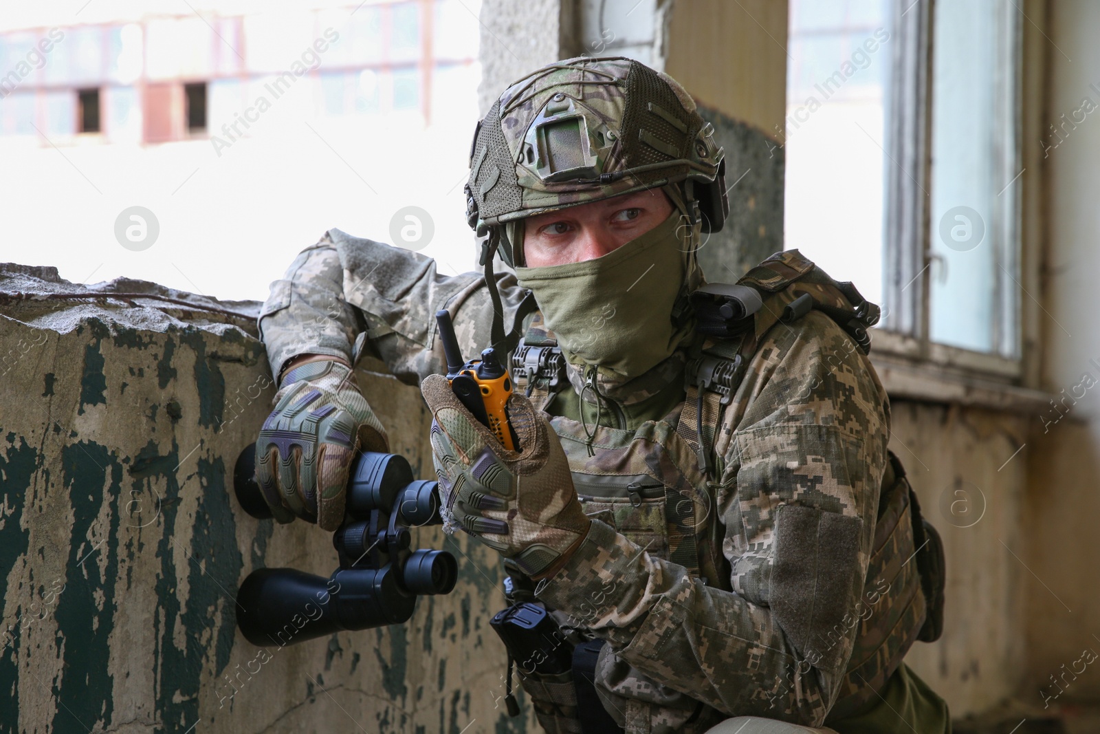 Photo of Military mission. Soldier in uniform with radio transmitter inside abandoned building