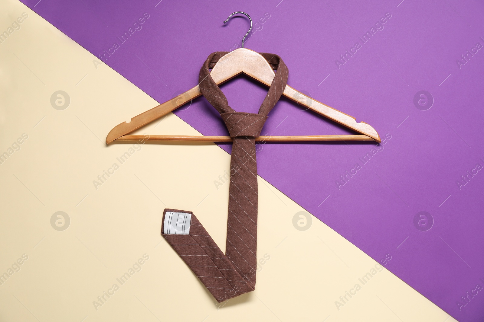 Photo of Hanger with necktie on color background, top view