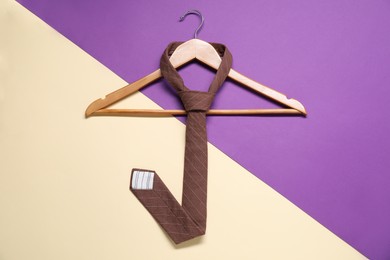 Hanger with necktie on color background, top view