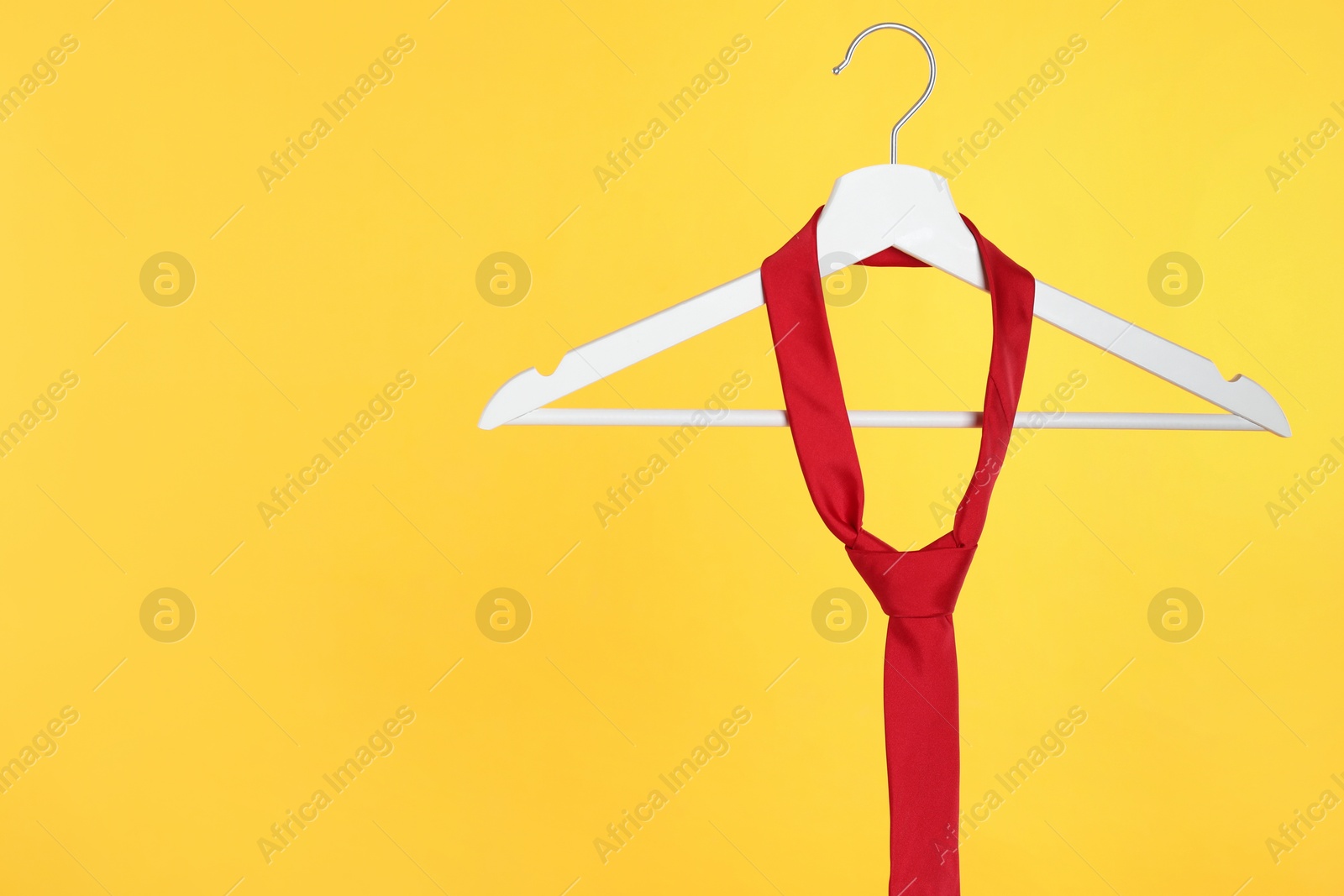 Photo of Hanger with red tie against orange background. Space for text