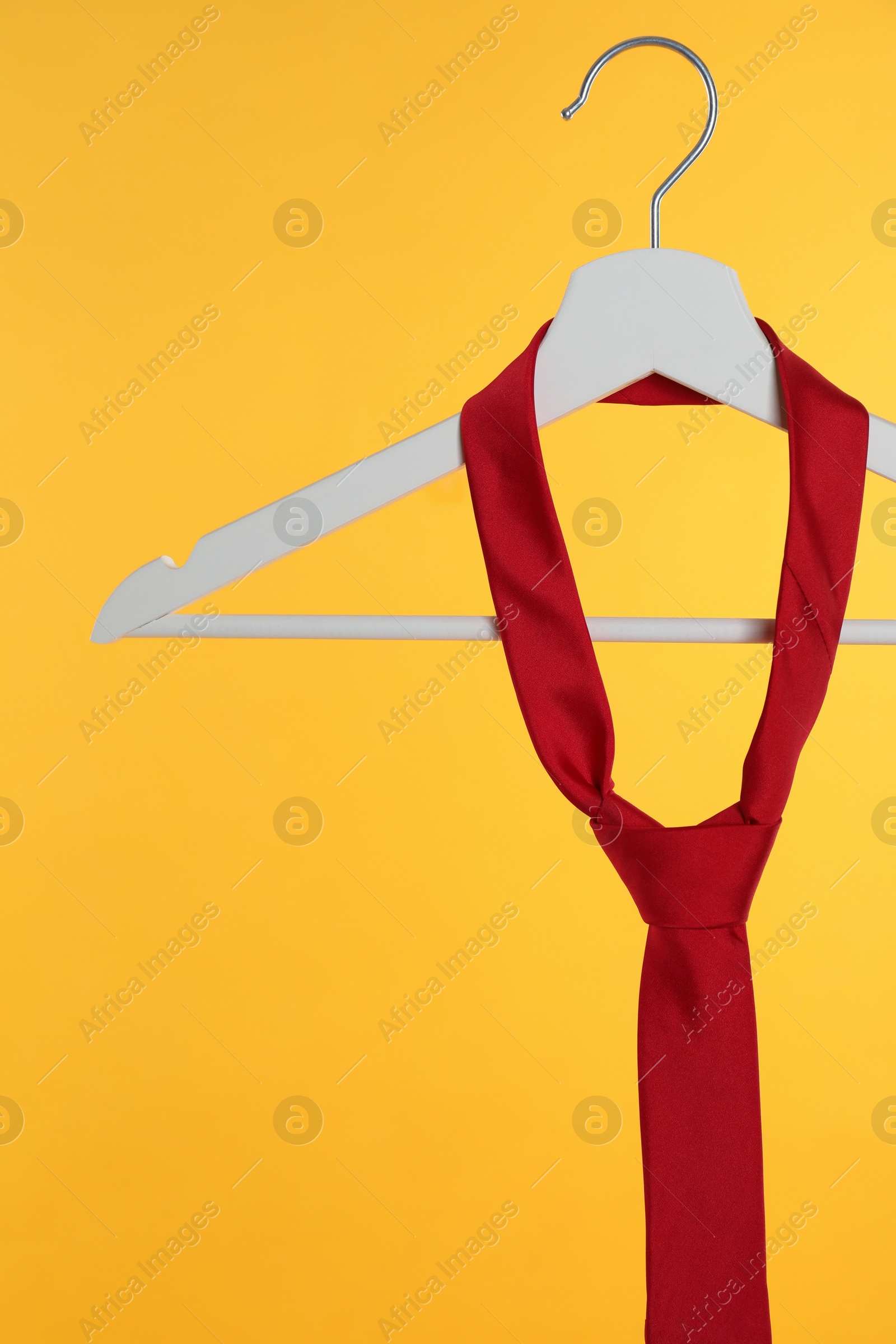 Photo of Hanger with red tie against orange background