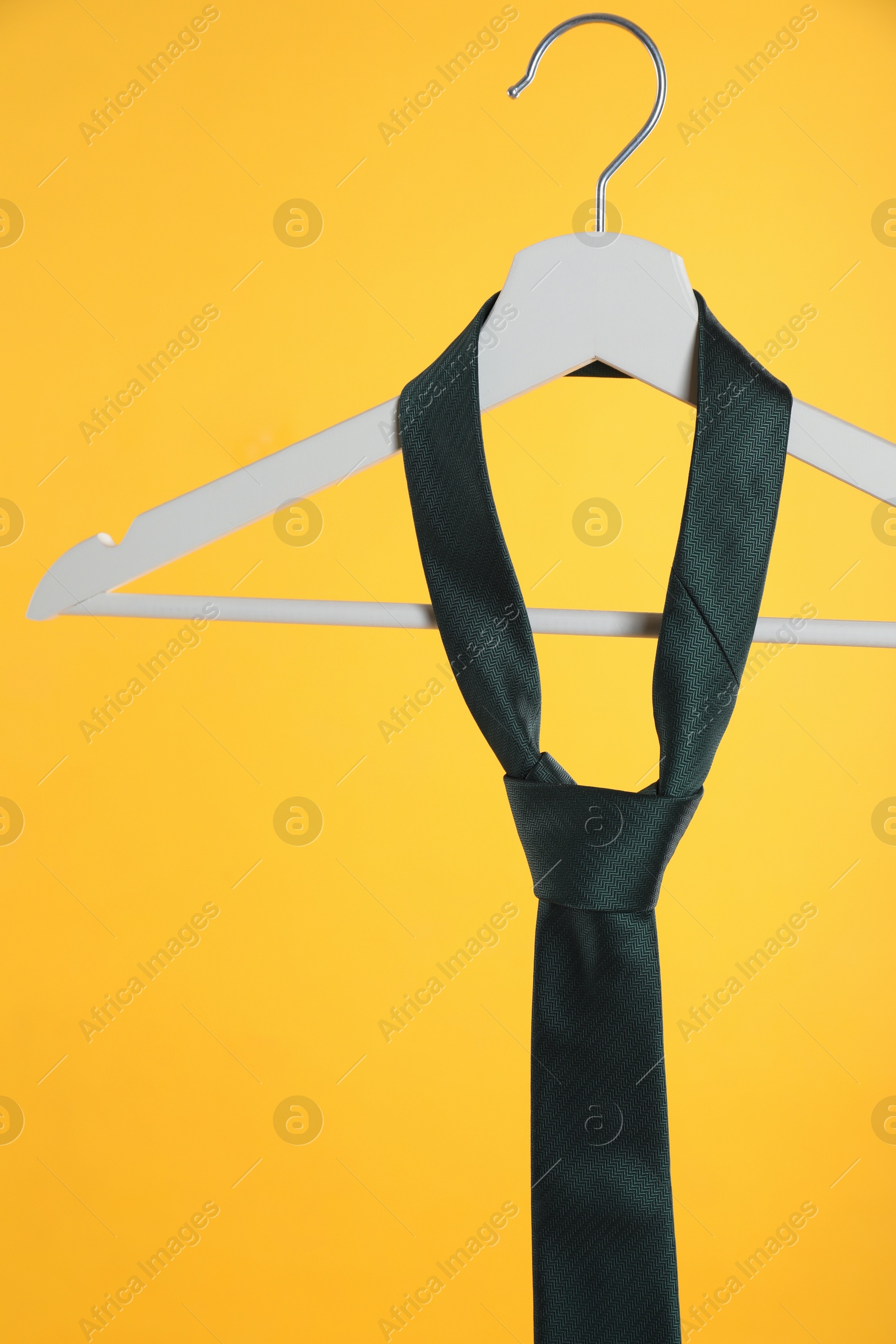 Photo of Hanger with black tie against orange background