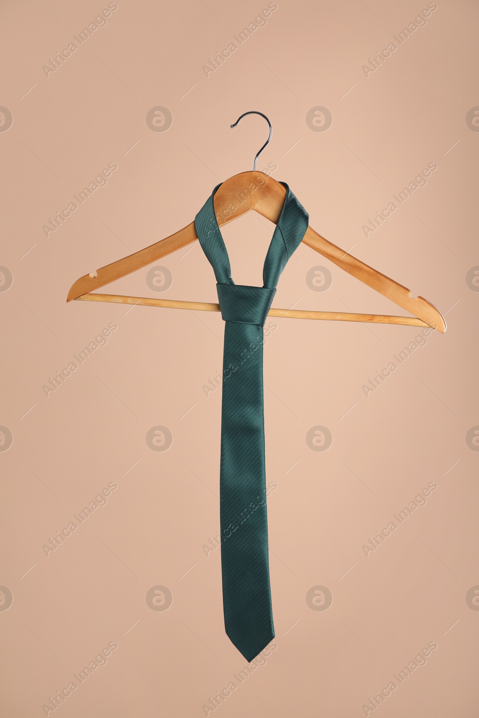 Photo of Hanger with teal tie on light brown background