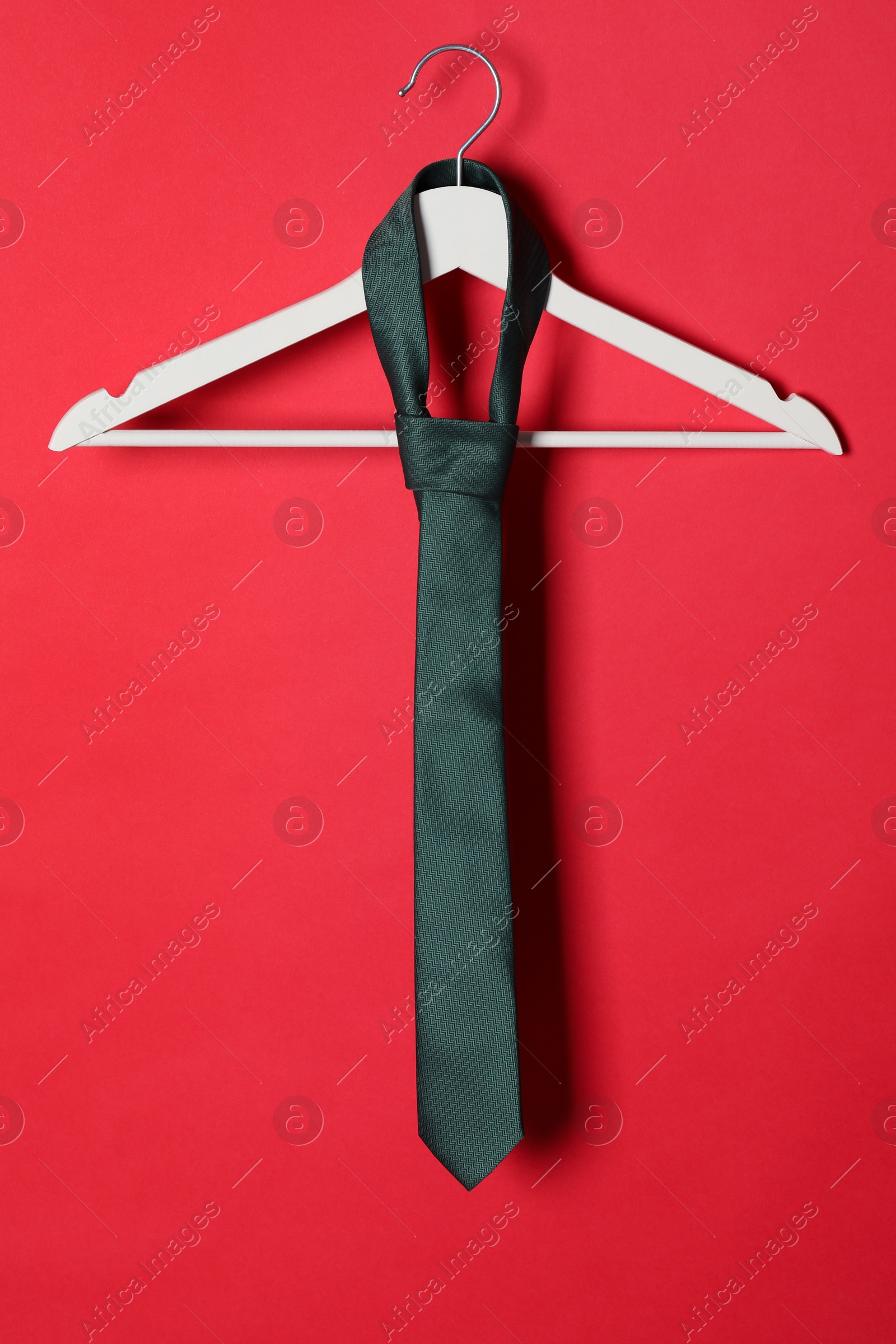 Photo of Hanger with black tie on red background