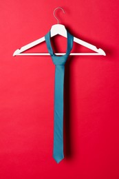 Photo of Hanger with dark turquoise tie on red background
