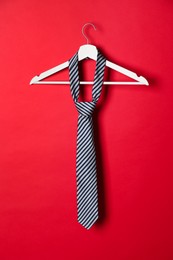 Hanger with striped tie on red background