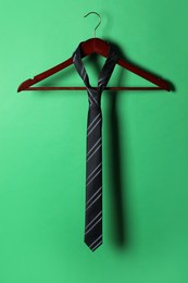 Hanger with black striped tie on green background