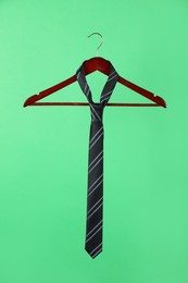Hanger with black striped tie on green background